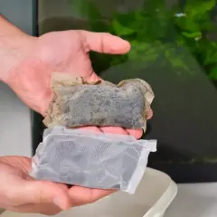 Dwie saszetki z węglem aktywnym, jedna nowa, druga używana, gotowe do umieszczenia w akwarium.