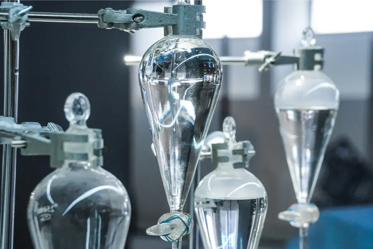 Laboratory setup z kolbami do rozdzielania cieczy. Woda destylowana i demineralizowana w szklanych naczyniach.