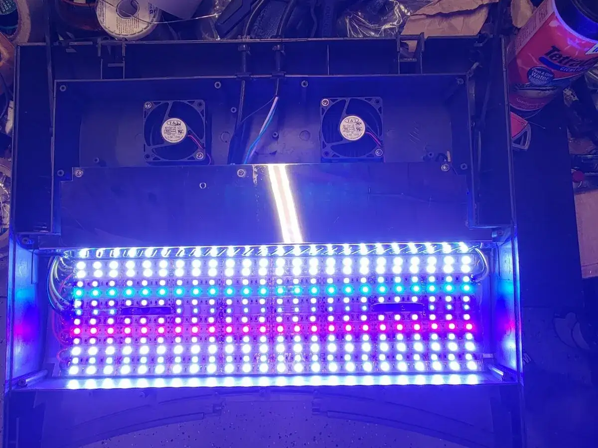 Wnętrze lampy LED z wentylatorami i rzędem białych, niebieskich i różowych diod. Odbłyśnik odbija światło.